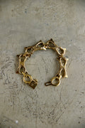 A vintage gold-tone chain bracelet with star-shaped links and a lobster clasp, displayed on a textured, scratched gray surface.