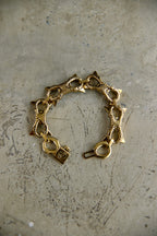 A vintage gold-tone chain bracelet with star-shaped links and a lobster clasp, displayed on a textured, scratched gray surface.